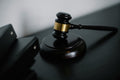 Wooden gavel on a dark surface with a neutral background.